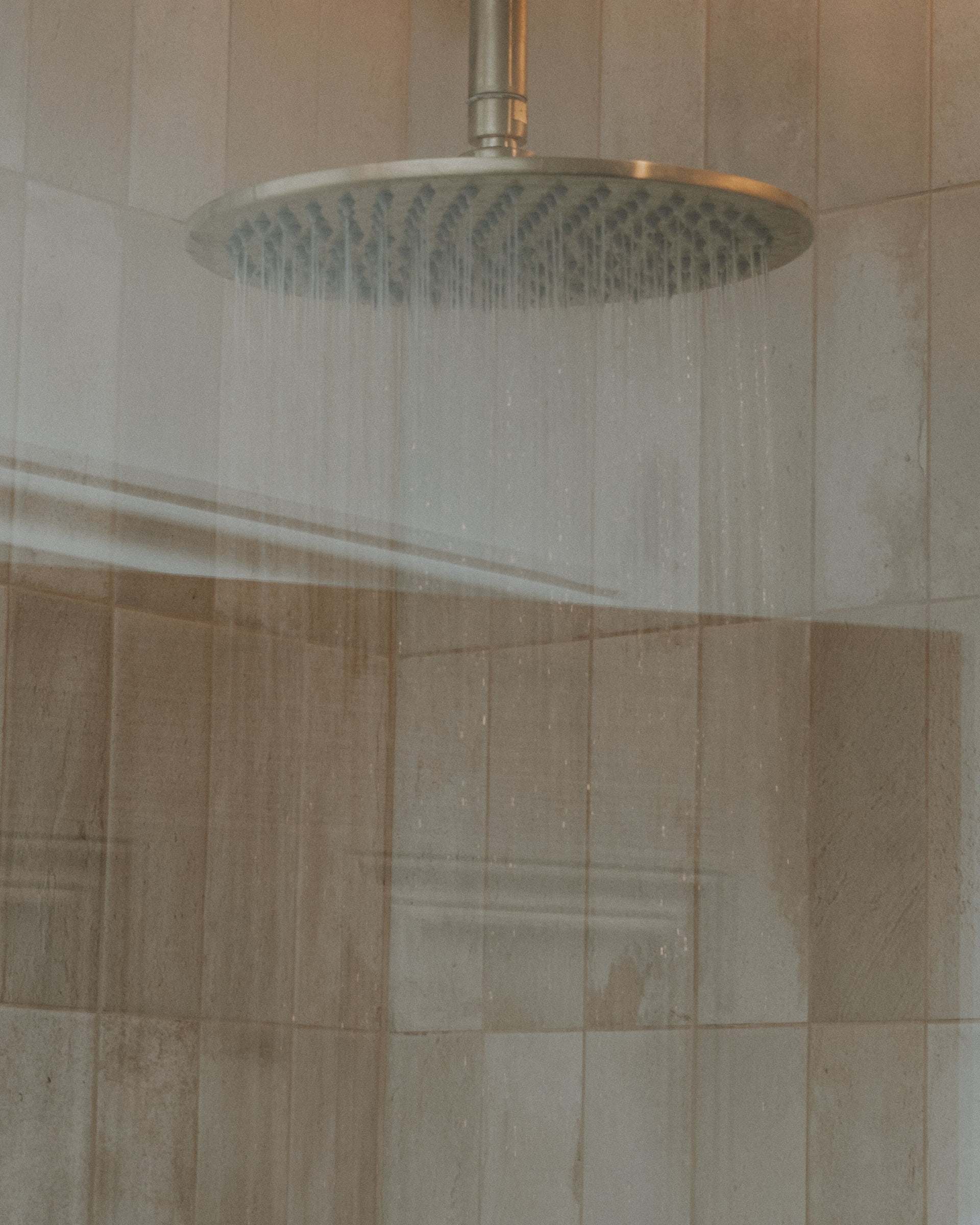 Rainfall shower head over carefully set wall tiles