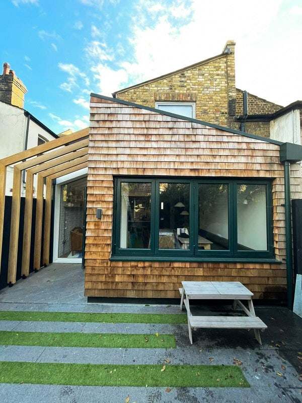 Timber-shingle clad rear extension with black glazing and a small garden