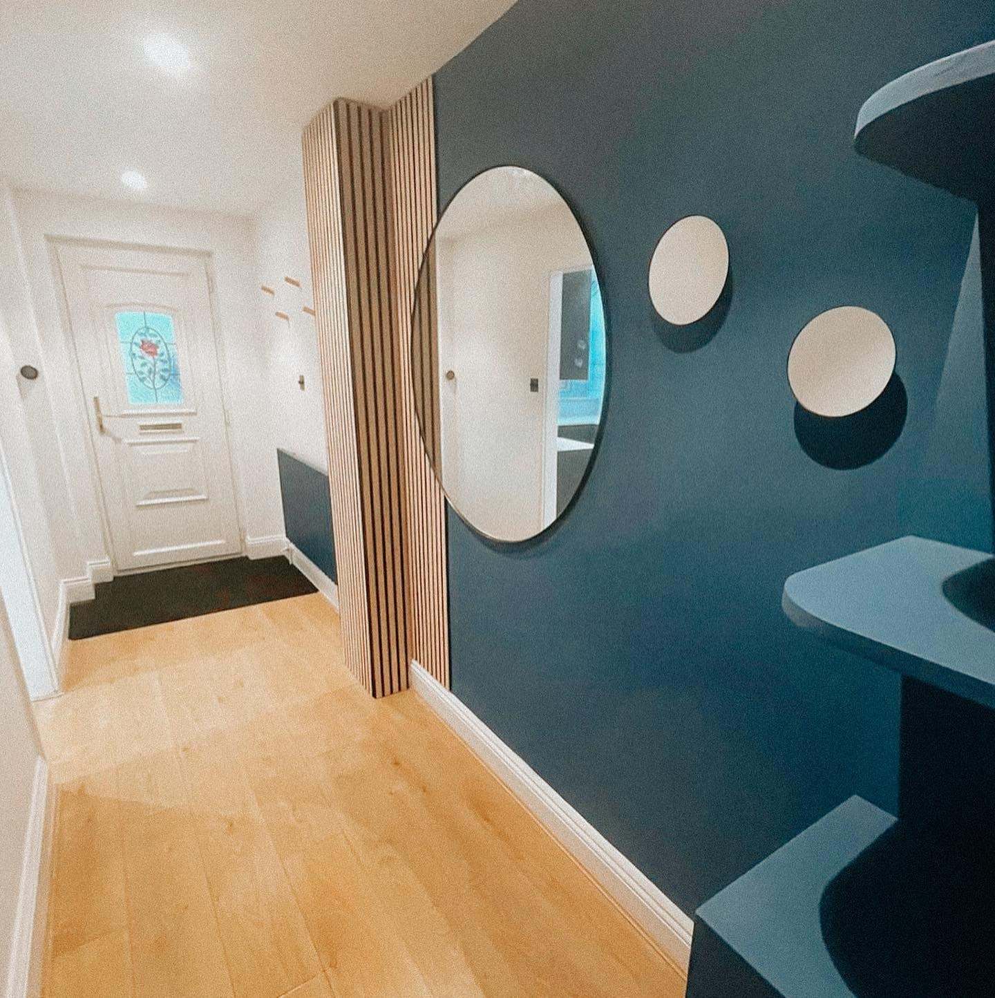 Rigge Place hallway with a vertical timber slat panel and round mirrors